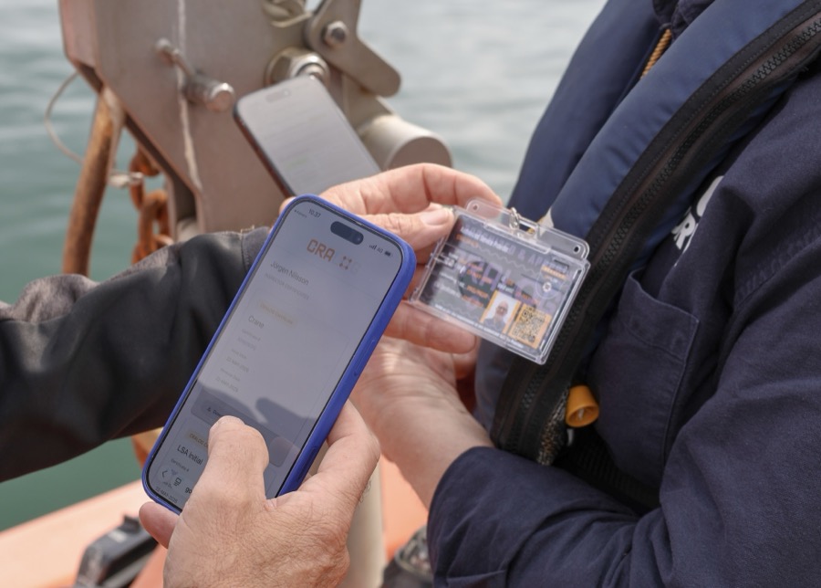 An inspector's CRALOG ID card with a QR code being scanned and verified on a phone